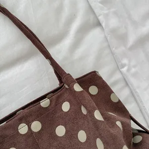 Detalle de primer plano de un bolso tote de ante marrón con estampado de topos.