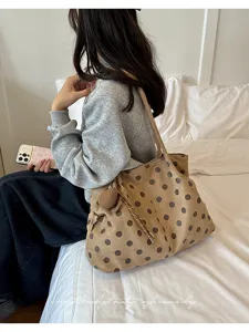 Vista detallada de bolso tote marrón de lunares estilo vintage con colgante en dormitorio.