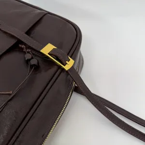 Dark brown leather bag detail close-up showing stylish metal buckle strap and vintage texture.