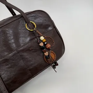 Korean retro dark brown Boston bag with shoulder strap and cute beaded pendant detail.