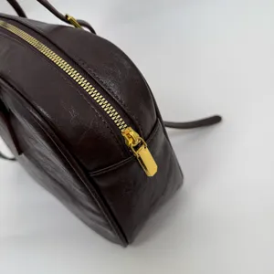 Detailed shot of dark brown Boston bag zipper and PU leather texture, chic minimalist design.