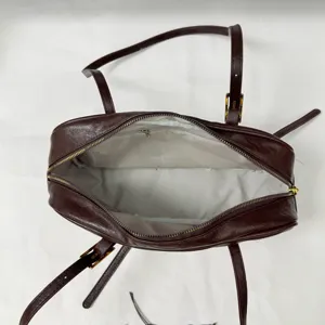 Detail view of brown vintage Boston shoulder bag with top zipper and long straps.
