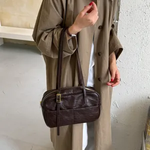 Detail view of a retro dark brown leather shoulder bag with double straps and metal buckle.