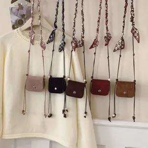 Mini suede crossbody bag for women, cute lipstick pouch with chic silk scarf strap design.