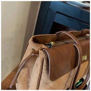 Dettaglio borsa a tracolla in camoscio marrone, elegante borsa casual con serratura e zip.