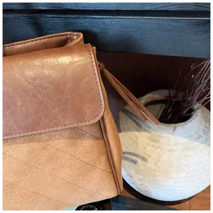 Primo piano di una elegante borsa a tracolla trapuntata marrone con design a patta e cuciture.