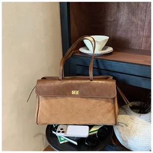 Vista dettagliata della borsa a tracolla baguette trapuntata marrone con chiusura e manici.