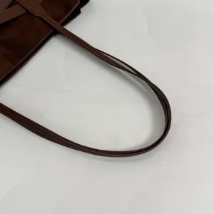 Λεπτομέρεια λαβής καφέ τσάντας σουέτ tote, μινιμαλιστικός σχεδιασμός, κοντινό πλάνο τσάντας.