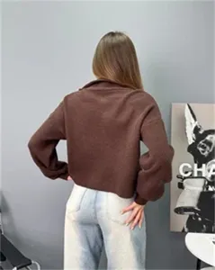 Détail d'un pull en tricot marron ample à demi-zip élégant et confortable pour femme.