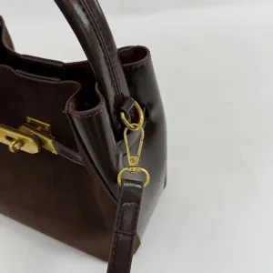 Detail view of brown suede handbag hardware, golden metal lock and strap clasp craftsmanship.