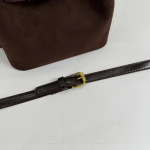 Brown suede bucket bag detail showing the adjustable shoulder strap and golden metal buckle.