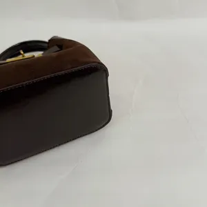 Detailed view of brown suede and leather bucket shoulder bag with gold hardware and vintage style.