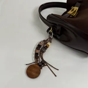Close-up view of the vintage brown suede handbag showcasing the elegant wooden bead charm detail.