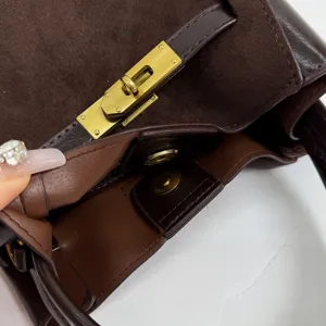 Detail shot of brown suede and leather handbag with metal lock hardware for women.