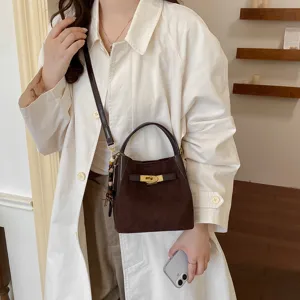 Detailed view of dark brown suede bucket bag with gold lock and stylish shoulder strap.