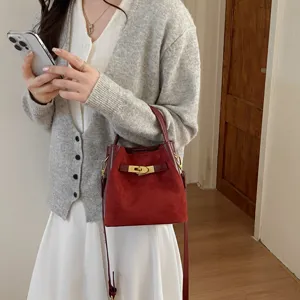 Chic burgundy suede bucket bag with stylish golden lock closure, versatile shoulder bag.