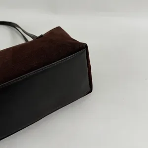 Détail de sac à bandoulière en suède marron et cuir noir, design vintage minimaliste chic.