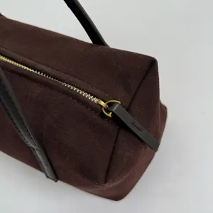 Détail de sac porté épaule oreiller en suédine marron, sac sous les aisselles rétro avec zip doré.
