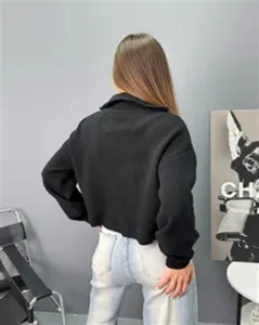 Détail du dos du pull en tricot noir à demi-zip, coupe ample et manches longues.