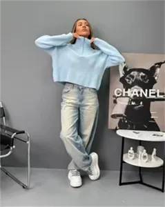 Vue détaillée du pull en tricot bleu clair à demi-fermeture éclair dans le studio décontracté.
