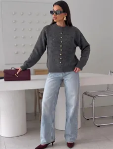 Detailaufnahme eines eleganten dunkelgrauen Strickpullovers mit goldenen Knöpfen im Raum.