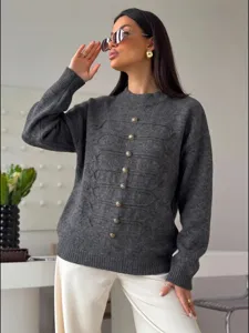 Detailaufnahme des eleganten dunkelgrauen Pullovers mit verzierten goldenen Knöpfen.
