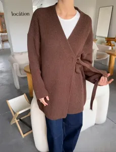 Detailopname van het bruine dames gebreide wikkelvest met tailleceintuur en gezellige stijl.