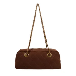 Close-up detail of the brown suede quilted shoulder bag featuring elegant chain straps.