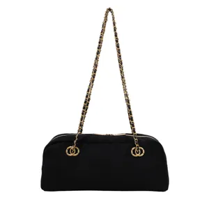 Detail view of black quilted chain shoulder bag with gold hardware and woven strap.