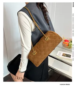 Brown quilted suede shoulder bag, vintage baguette shape with elegant gold chain strap detail.