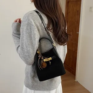 Elegant black suede bucket bag for women, featuring metal lock closure and stylish strap details.
