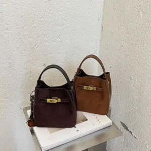 Vintage minimalist suede bucket bag with top handle and metal lock closure for women.