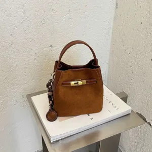 Retro brown suede bucket bag with top handle and metal lock. Stylish women's handbag.