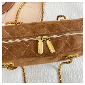 Brown quilted suede bowling shoulder bag with gold chain hardware and dual zip closure.