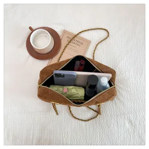 Detail shot of retro quilted suede bowling shoulder bag with gold chain strap, spacious interior.