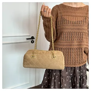 Detailed view of the vintage brown suede quilted bowling bag with chic chain strap.