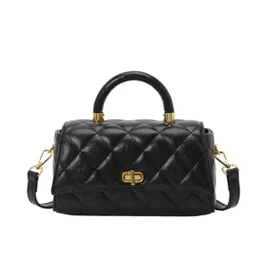 Dettaglio della borsa a mano nera matelassé con motivo a rombi e chiusura girevole dorata elegante.