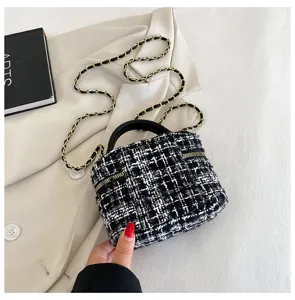 Detailopname van een zwart-witte tweed ketting minischoudertas met handvat en chique look.
