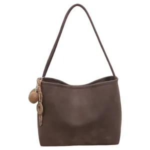 Detailed view of the dark brown shoulder bag strap, minimalist tote design and braided charm.