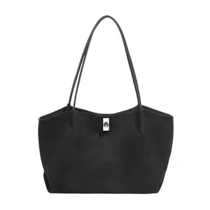 Black suede tote bag detail, minimalist shoulder bag with thin straps and metallic clasp closure.