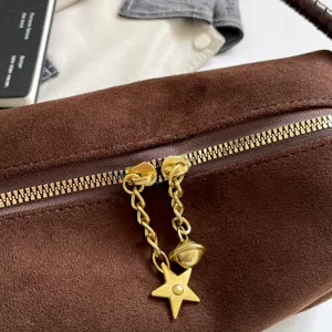 Close-up view of the brown suede handbag zipper and stylish gold star pendant detail.