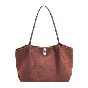 Detail view of brown suede tote bag, minimalist style with slim double handles and metal clasp.