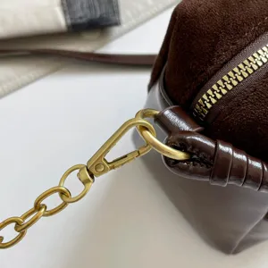 Brown suede leather shoulder bag detail with gold hardware zipper and chain strap.