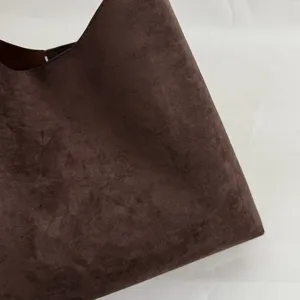 Close-up detail of luxury brown suede handbag fabric texture, soft minimalist hobo bucket bag.