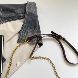 Detail view of the stylish shoulder bag showcasing denim and leather splicing with chic chain.