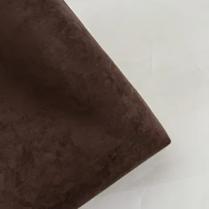 Brown suede handbag material detail view, showcasing soft fabric texture and fine craftsmanship.