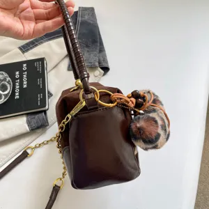 Brown suede patchwork pillow bag featuring metal chain strap and leopard plush charm.