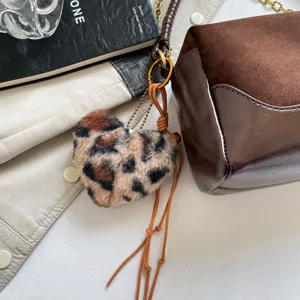 Brown suede and leather pillow shoulder bag detail showcasing leopard plush keychain accessory.