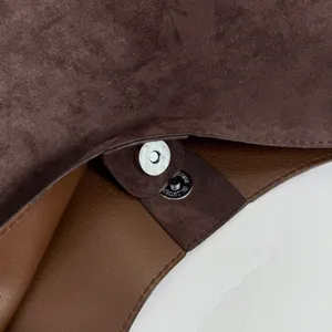 Detail shot of brown suede handbag interior with magnetic snap closure, premium texture.