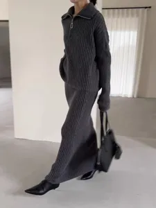 Detail view of a cozy dark grey ribbed knit half-zip sweater and long skirt set.